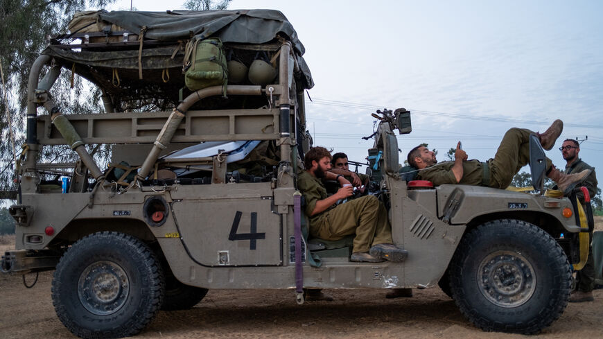 IDF reservists rest on a military vehicle while at a rest stop where food is prepared by volunteers on November 13, 2023 in Southern Israel.